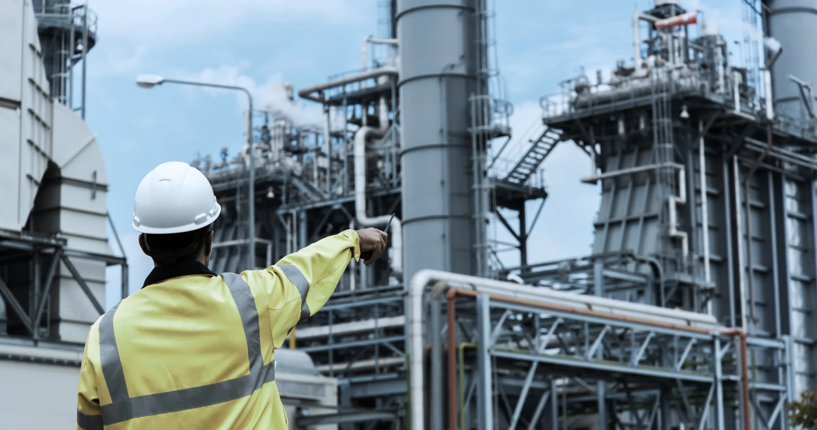 a worker pointing at a large industrial setup