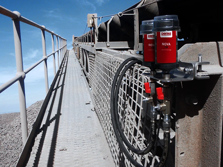 two perma NOVA automatic lubricators remote mounted to a conveyor