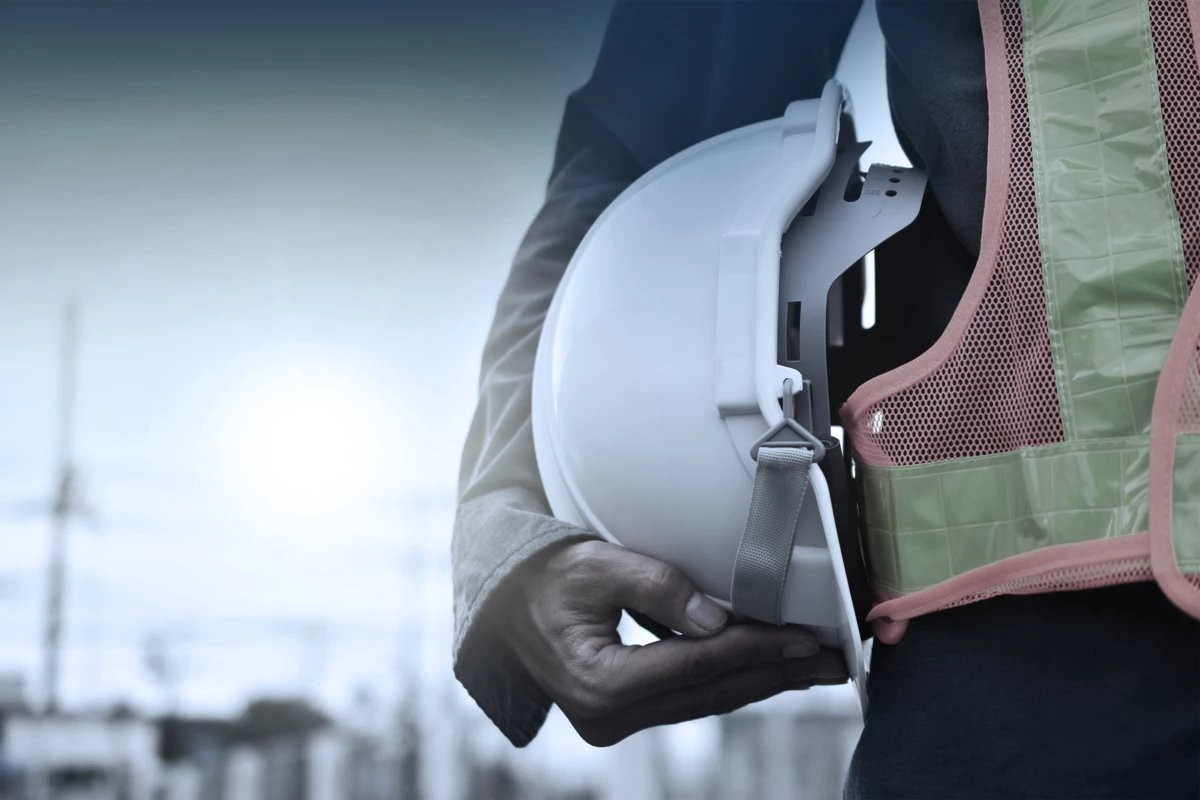 a worker holding a hard hat and wearing a high visibility vest