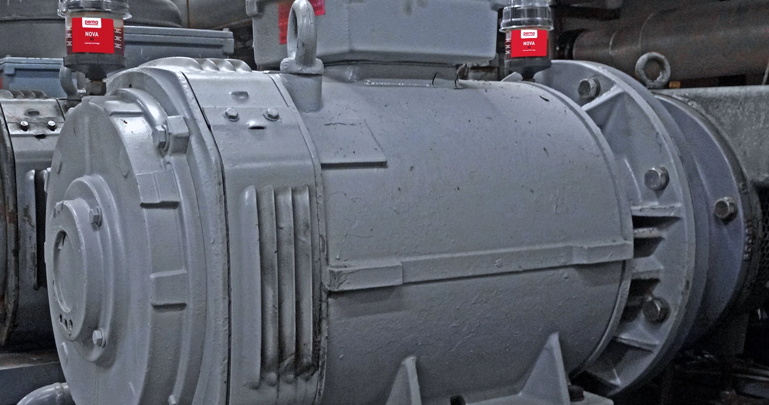 two perma Flex auto greasers directly mounted to a piece of industrial machinery