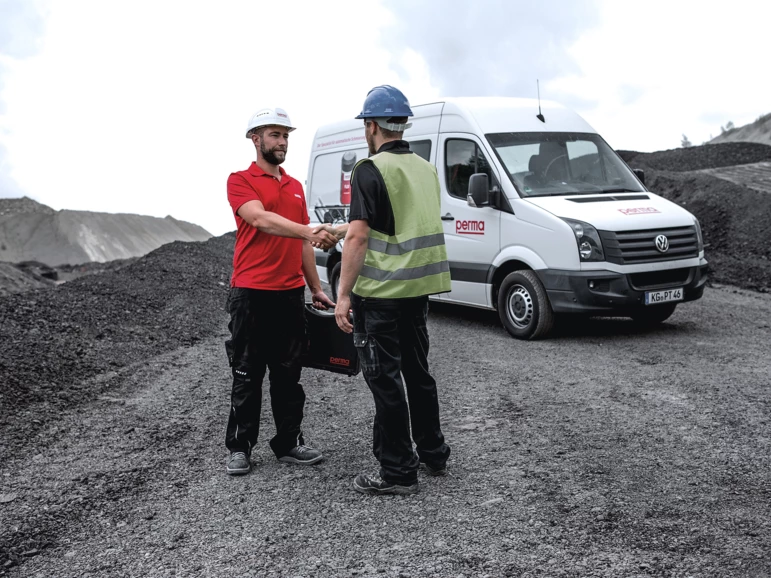 a perma service technician and a plant worker shaking hands
