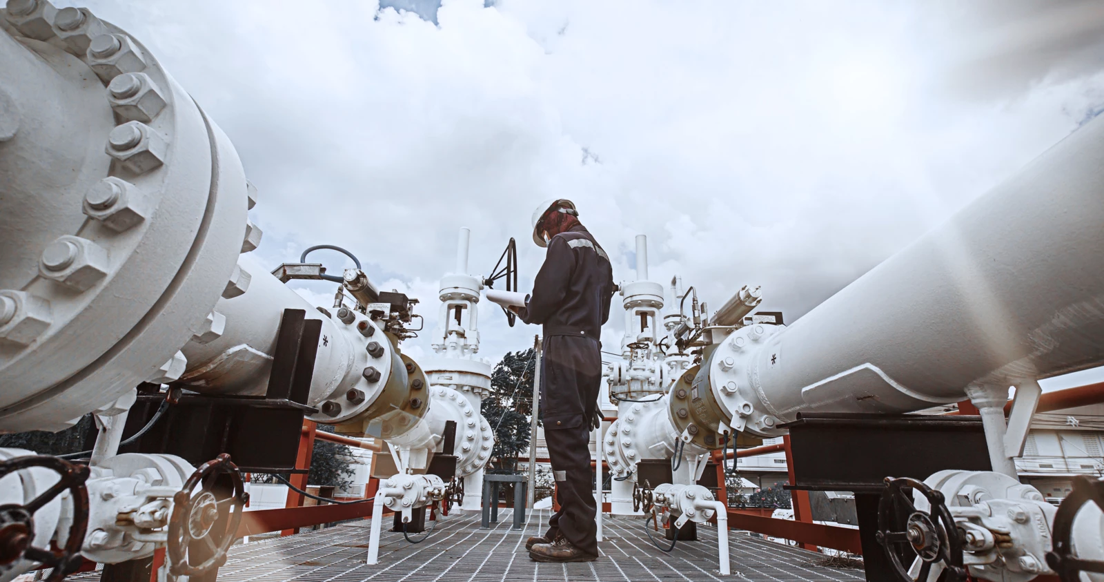 A worker standing in between two industrial pipes